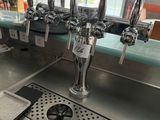 a metal counter with a bunch of beer taps on it
