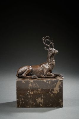 bronze sculpture of a deer lying down on a marble block