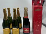 six bouteilles de champagne sont alignées les unes à côté des autres près d'une boîte rouge