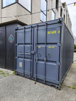 un conteneur d'expédition bleu posé devant un immeuble