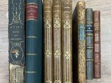 Plusieurs vieux livres sont alignés sur une étagère posée sur une table en bois