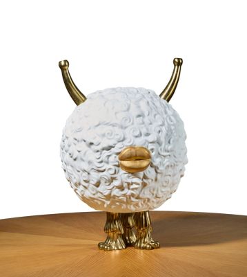 une sculpture blanche et dorée représentant un mouton, posée sur une table