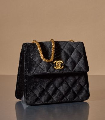 a close up of a black purse on a table with a gold chain