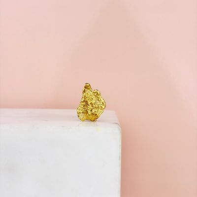 a gold leaf ring sitting on top of a white marble block