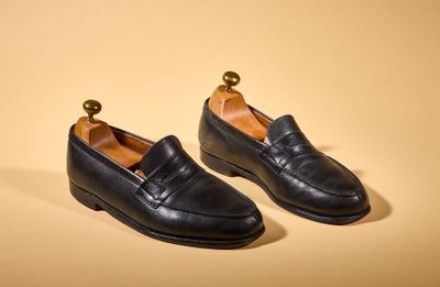 a pair of black leather shoes on a yellow background