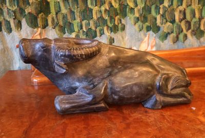 une statue représentant un taureau assis sur une table en bois