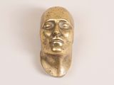 brass statue of a man ' s head on a white surface