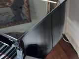 a black piano sitting on a wooden floor in a living room