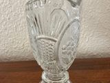 a glass vase sitting on a table with a white wall in the background