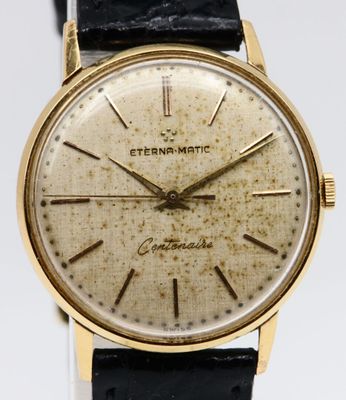a close up of a gold wrist watch on a black leather strap