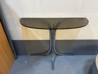 une petite table avec un plateau en verre posée à même le sol