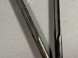 two metal tools that are laying on a white surface