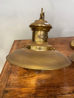 une paire de lampes en laiton posées sur une table en bois, avec un mur blanc en arrière-plan