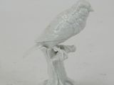 porcelain figurine of a bird perched on a branch on a white background