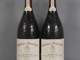 Deux bouteilles de vin sont posées sur une table en verre, sur un fond gris.