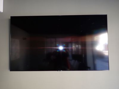 a television mounted on the wall with a person taking a picture of it