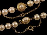 a close up of a necklace with pearls on a chain