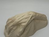 a clay sculpture of a frog on a white surface
