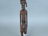une vieille statue en bois d'un homme avec un chapeau sur la tête