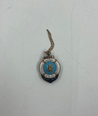 un gros plan d'un collier orné d'une boussole, posé sur une surface blanche