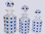 three glass bottles with blue dots are lined up on a white surface