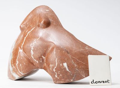 une sculpture en marbre représentant un chien, avec une médaille posée devant lui