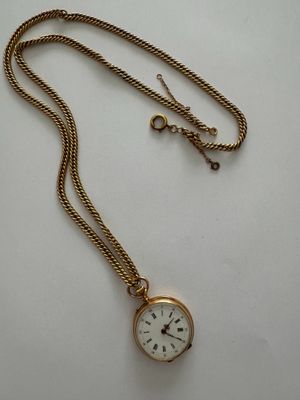 an antique pocket watch with a chain on a white surface