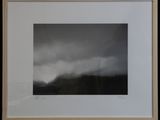 a black and white photograph of a mountain with clouds in the sky