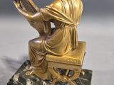 statue of a woman sitting on a chair playing a harp