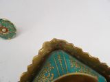 a blue and gold vase sitting on a table next to a small object