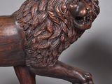 a wooden statue of a lion with a ball in its paws