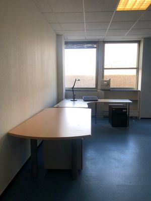 une longue table au milieu d'une pièce dotée de deux fenêtres