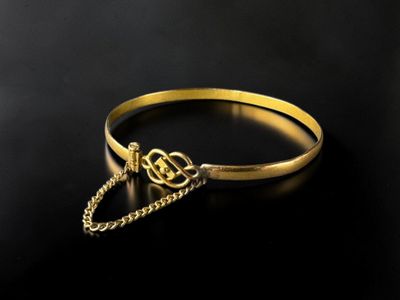 a close up of a gold bracelet with a chain around it