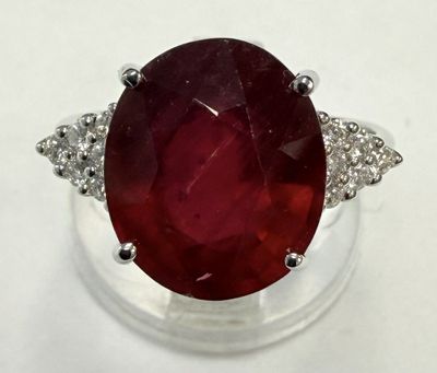 gros plan d'une bague avec une pierre rouge entourée de diamants blancs