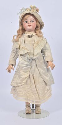 une poupée ancienne représentant une femme vêtue d'une robe blanche et d'un chapeau