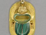 une image représentant un pendentif doré et vert orné d'une statuette représentant une femme