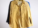 two jackets hanging on a hanger in front of a white wall
