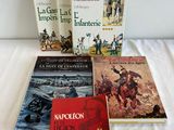 four books are sitting on a bed with a white sheet
