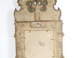 an old mirror hanging on a wall with a white background