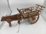 a wooden horse pulling a wooden cart with a rope