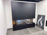 une cheminée dans un coin d'une pièce où est accroché un tableau au mur