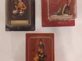 three miniature figurines of a woman sitting on top of a table