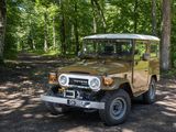 a brown and white jeep parked in a wooded area