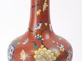 un vase rouge orné d'un motif floral