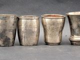 six silver cups lined up in a row on a table