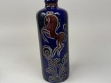 a blue bottle with a design on it on a white surface