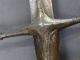 a close up of a sword on a gray surface