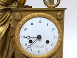 a gold clock with a statue of a woman sitting on top of it