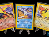 Trois cartes Pokémon différentes sont représentées sur un fond noir.