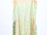 a green top hanging on a hanger on a white wall